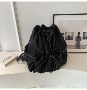 Close-up of black nylon drawstring backpack featuring side zippers and plastic buckle details
