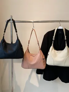 Minimalist half-moon underarm bags in black, pink, and beige with adjustable straps