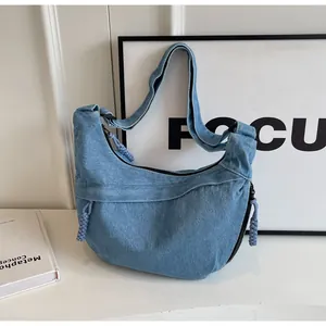 Détail du sac demi-lune en jean bleu clair avec cordes tressées et fermeture éclair