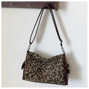 Zijaanzicht van luipaardprint tote bag met bruine leren riemen hangend aan een houten haak