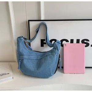Vue détaillée du sac demi-lune en jean bleu avec tablette rose pour référence de taille