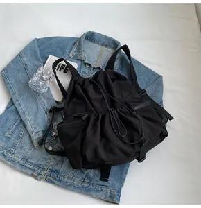 Detail of black nylon drawstring backpack with functional zippers on a lifestyle background