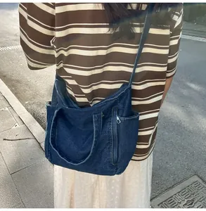 Detail of blue denim tote bag with functional side pockets and dual handle design