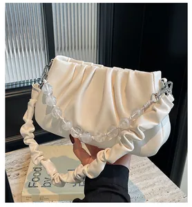 Detail van witte geplooide cloud bag met decoratieve kralenketting