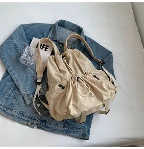 Detailed close-up of beige nylon drawstring backpack on denim fabric background