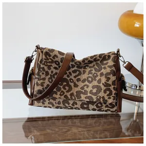 Detail van de luipaard tote tas met bruine lederen bies en retro metalen gespen