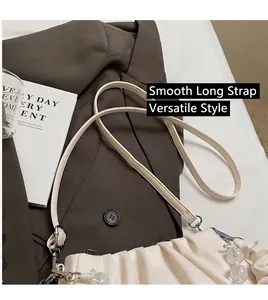 Gedetailleerd beeld van de crème geplooide handtas met lange riem en kralenhanger