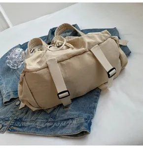 Detail of khaki nylon backpack with drawstrings and decorative straps on denim