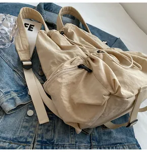 Detail view of khaki nylon drawstring backpack showing zipper pocket and adjustable straps