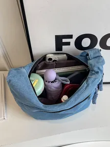Grand sac bandoulière en denim bleu montrant un intérieur spacieux avec accessoires