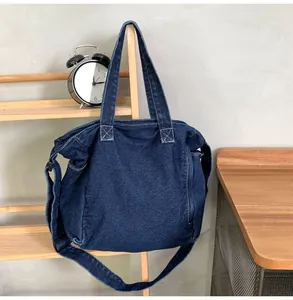 Close-up of deep blue denim messenger bag with white stitching and adjustable strap