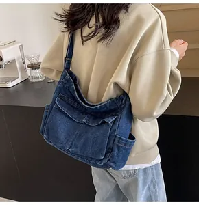 Detail of deep blue denim crossbody bag with utility pockets shown on model