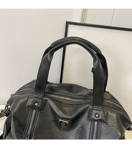 Close-up of black leather tote bag featuring metal logo, studs and soft dual handles