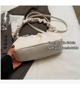 Detail van crème geplooide cloud bag met zachte textuur en parelsluiting