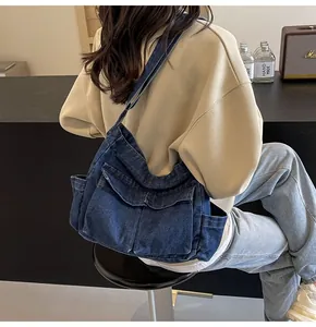 Detail view of a blue denim shoulder bag with multi-pocket utility cargo design on a model