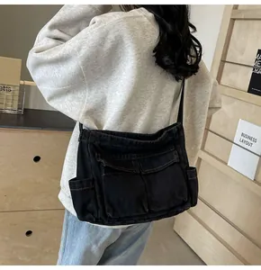 Detail view of black denim crossbody bag with contrast stitching and dual cargo pockets