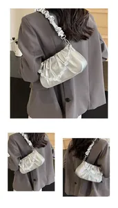 Detail van zilveren metallic cloud bag met kralenketting en brede geplooide schouderband