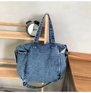 Detail of vintage washed blue denim messenger bag showing side pockets and stitching