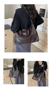 Detail of dark brown leather tote with metal shield logo and multi-zipper compartments