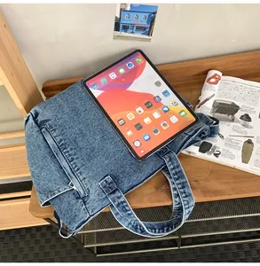 Detail of blue denim tote bag with iPad and magazine on wooden surface for size context