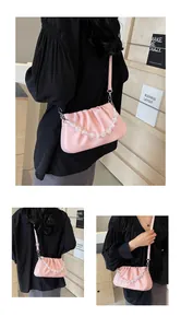 Close-up van roze geplooide cloud bag met kristallen parelketting en dunne schouderriem