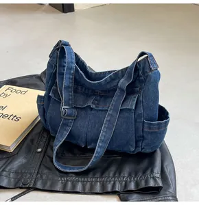 Detail of blue denim crossbody bag featuring utility pockets and adjustable strap