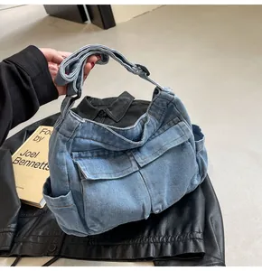 Detail of light blue washed denim crossbody bag featuring multiple cargo utility pockets