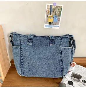 Detail of vintage acid wash denim messenger bag showing multi-pocket large capacity design