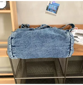 Macro shot of washed blue denim messenger bag with wide shoulder strap on wooden shelf
