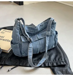 Detail of washed blue denim shoulder bag featuring multiple functional front flap pockets