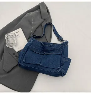 Macro shot of dark denim messenger bag showing front flap pockets and fabric texture