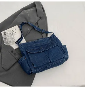 Detail of blue denim crossbody bag with large front flap pockets and adjustable strap