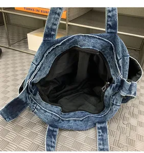 Detail of blue denim messenger bag showing durable zipper closure and interior black lining