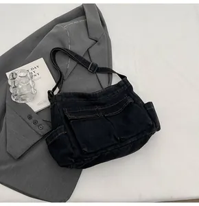 Detail of black denim crossbody bag featuring orange contrast stitching and cargo pockets