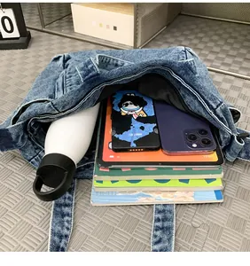 Blue washed denim messenger bag showing spacious interior with tablet and books
