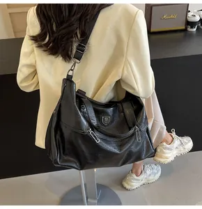 Detail of a black textured leather tote bag with silver hardware on a lifestyle model