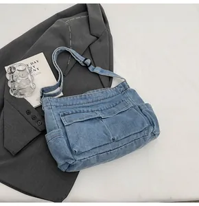 Detailed close-up of blue denim shoulder bag with functional pockets and wash texture