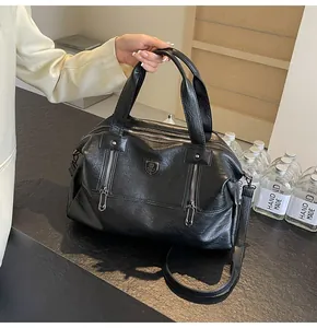 Detail view of black faux leather tote bag with metal zippers and crossbody strap