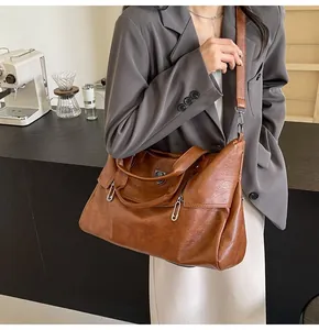 Brown soft PU leather tote bag shown on model with shoulder strap and metal detail
