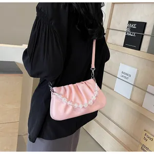 Detail van roze geplooide cloud bag met stijlvolle kralenketting en leren riem