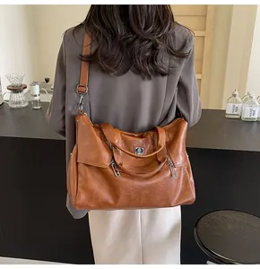 Close-up of a large brown vintage leather tote bag with a decorative metal zipper and strap