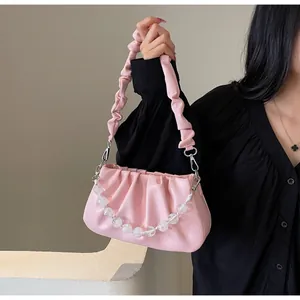 Detail van lichtroze gerimpelde cloud bag met kralenketting en geplooide schouderriem