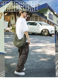 Olive green nylon crescent crossbody bag worn by male model in urban street setting
