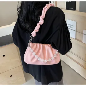 Detailweergave van de roze geplooide tas met elegante witte decoratieve kralenketting