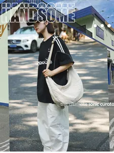 Close-up of beige nylon crescent bag with wide adjustable strap on a street model