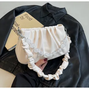 Detail van crème geplooide wolktas met transparante kralenketting en brede schouderband