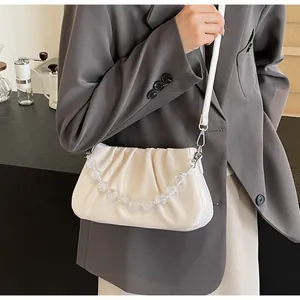 Detail van geplooide cloud bag met elegante parelketting en witte schouderband