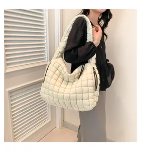 Detail van witte gewatteerde puffy tote bag met zwart trekkoord op de schouder van model