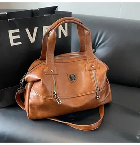 Detail of tan lychee textured leather tote featuring pin-shaped zippers and metal shield