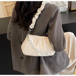 Detail van crèmewitte geplooide cloud bag met kralenketting en een geplooide schouderriem